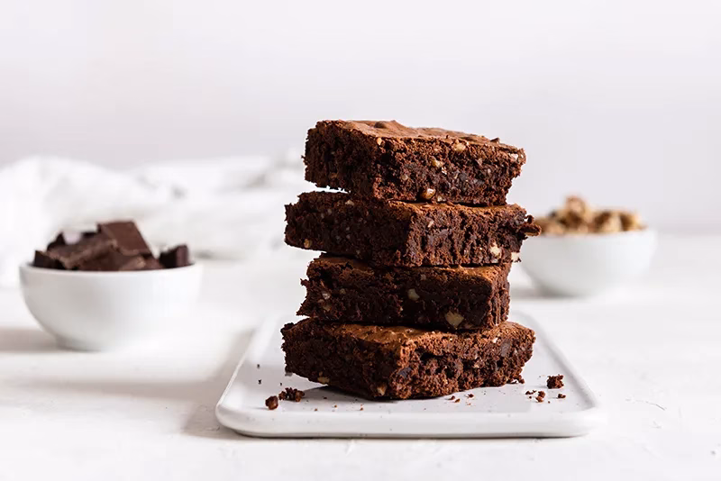 Pila de brownies de chocolate oscuro con trozos de nuez.