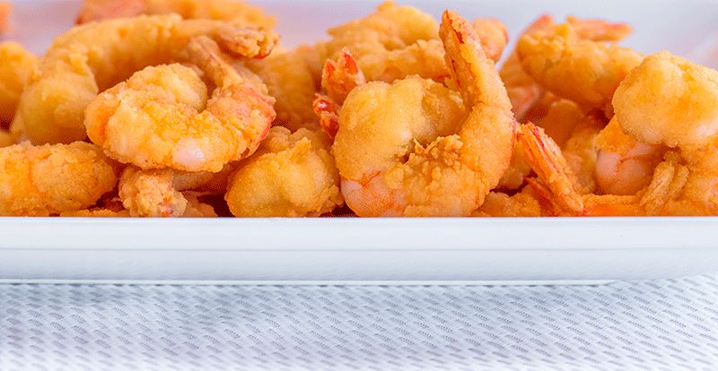 Camarones crocantes y dorados sobre bandeja blanca.