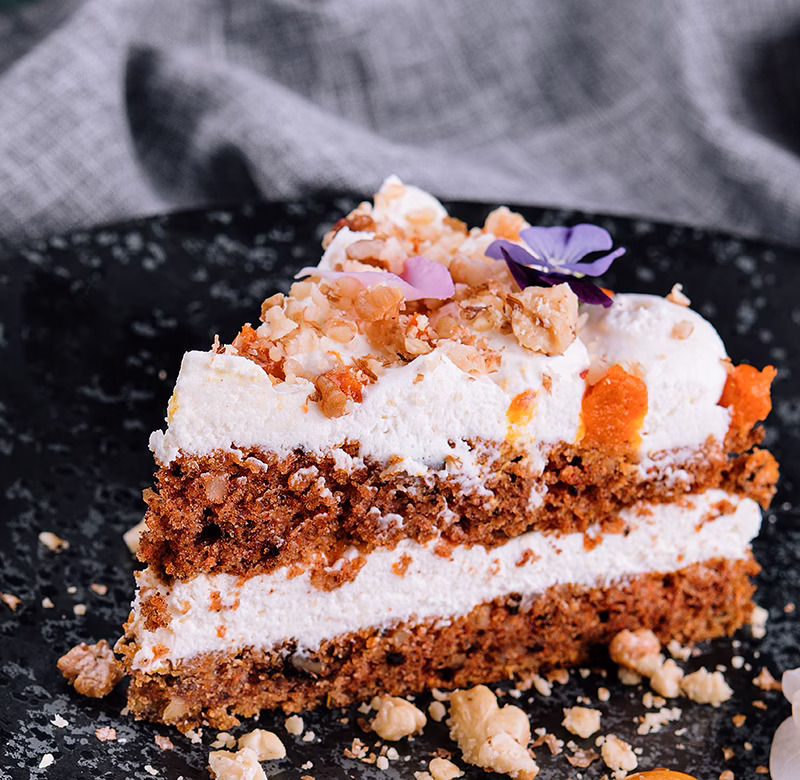 Porción de torta de zanahoria sobre un plato negro.
