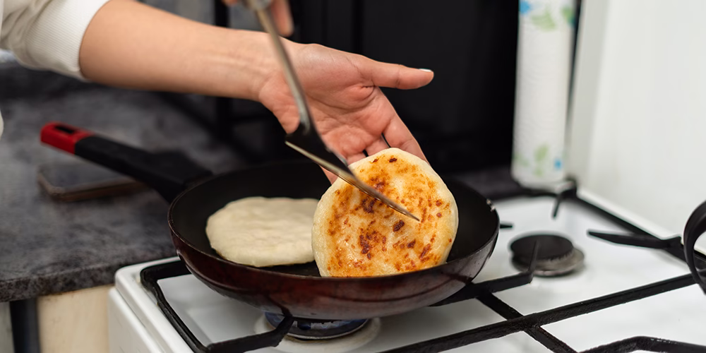 Asando arepas en una sartén sobre una estufa.